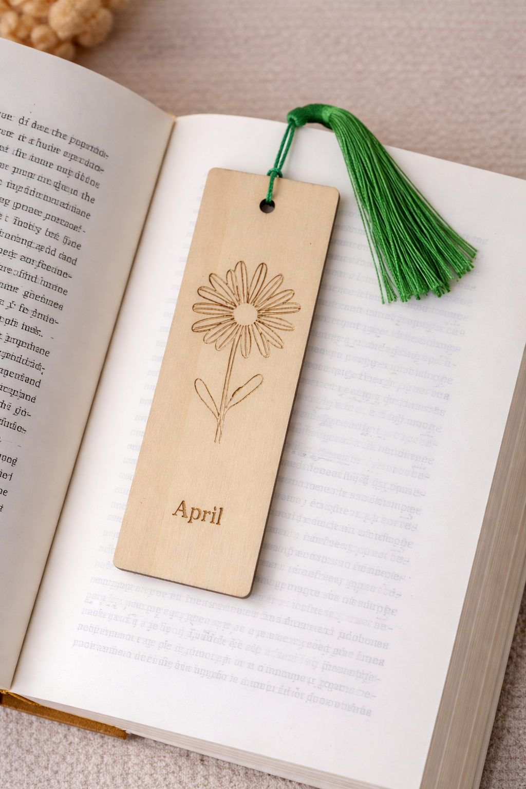 Wooden bookmark with floral design and green tassel on an open book