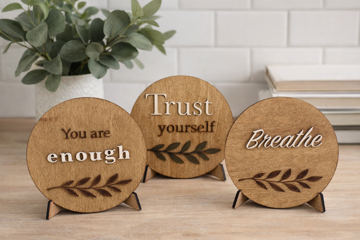 Three wooden circular signs with motivational phrases on a table.